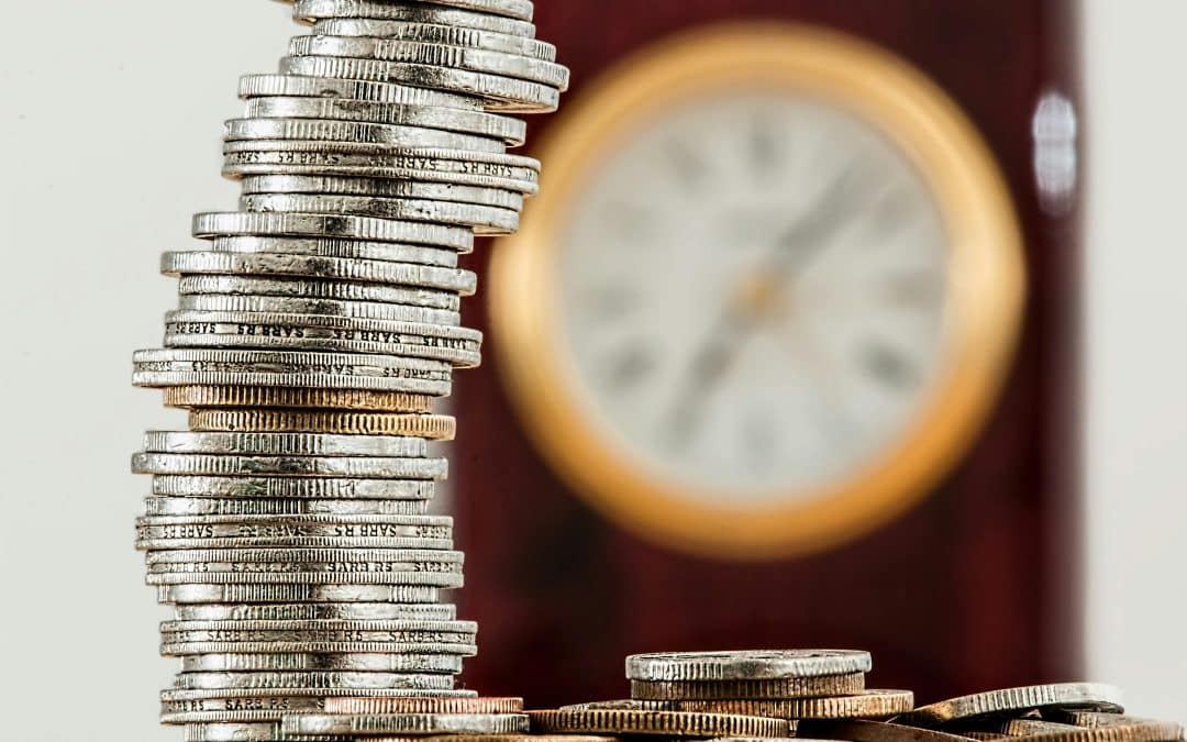 stack of coins in front of a clock